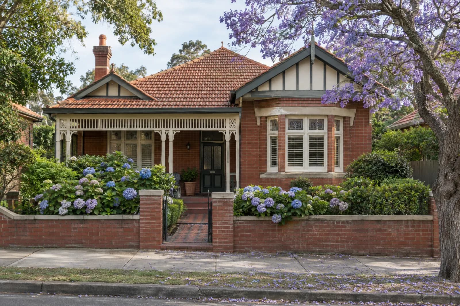 A Federation red-brick bungalow under a flowering jacaranda in Sydney