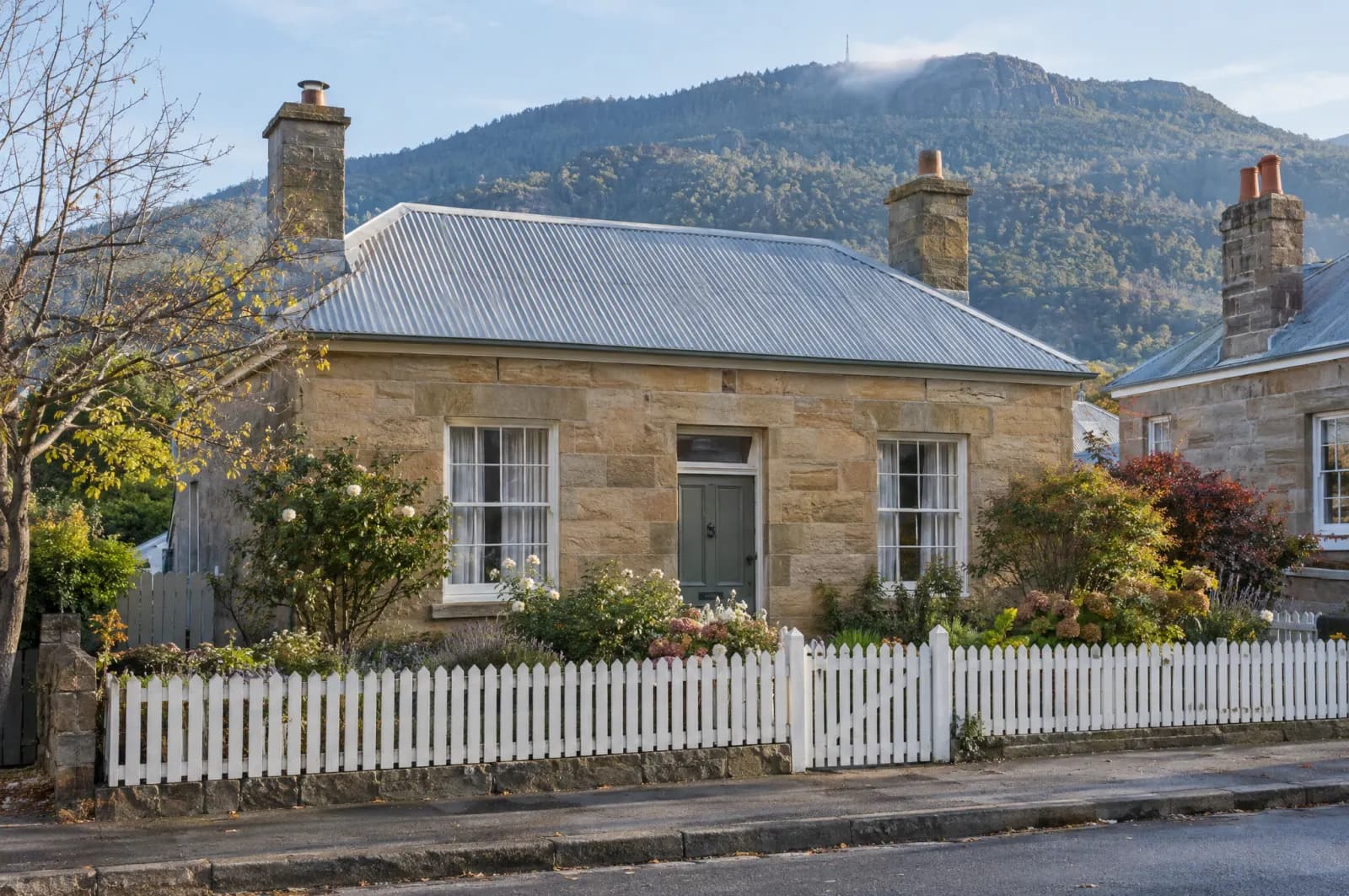 A Georgian sandstone cottage with a picket fence in Hobart